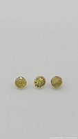 Close-up of 3 round cut natural African sphene gemstones showing their yellow-green color and facets