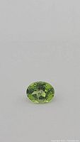 Close-up image showing the oval cut apple green Peridot gemstone with visible facets and color.