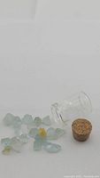 Natural aquamarine and one yellow heliodor beryl crystals laid out with glass vial and cork stopper