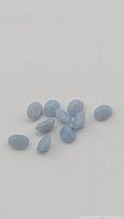Close-up of ten oval cut natural blue opal gemstones with robin's egg blue color on white background.