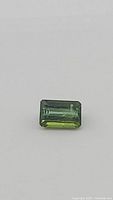 Close-up image of the natural bright green emerald cut tourmaline gemstone, showing facets, color and clarity.