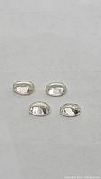 Four oval cut light champagne colored zircon gemstones arranged on a flat surface, showing their polished and faceted surface.