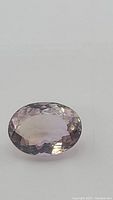 Close-up photo of the oval cut ametrine gemstone showing its transparent purple-yellow hues and faceted surface.