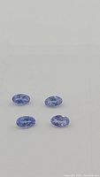 Close-up of four oval cut natural Tanzanite gemstones showing size, shape, and clarity.