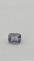 Close-up photo of the purple spinel gemstone showing its emerald cut and the vibrant, natural purple color with good clarity.