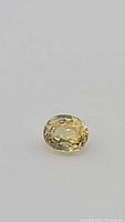 Close-up showing the bright yellow oval cut zircon gemstone with clear facets.