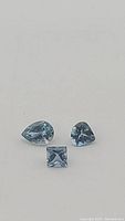 Front view of three loose aquamarine gemstones on white background