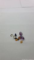 Loose assorted natural gemstones including amethyst, tiger's eye, labradorite, caramel opal, blue kyanite, citrine, and honey jade arranged on white background.