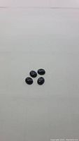 Four oval cabochon cut natural blue pietersite stones arranged on a plain surface.