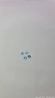 Photo showing four small, trillion cut Swiss blue topaz gemstones laid out on a white background