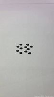 Eleven pear-shaped black onyx stones arranged on a white background showing their size and shape.