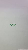 Photo of five small almost square green jade cabochon gemstones arranged on a flat surface under natural light.