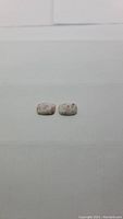 Two matching natural Mexican cinnabar cushion cabochon cut gemstones lying flat on a white surface, showing distinctive red cinnabar patch patterns on a cream background.