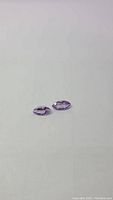 Two natural marquis cut purple amethyst gemstones, clear and well-matched in size and color, presented against a white background.