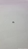 Photo of a single off white spinel gemstone placed on plain white background, showing size and color