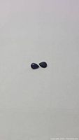 Two small pear shaped deep royal blue Kyanite gemstones side by side on plain white background showing their size and shape.