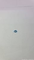 Photo of natural pear cut Swiss blue topaz gemstone on a white background, showing shape and color