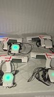 Four white Laser X laser tag guns and four chest sensors with glowing lights and black straps spread out on a surface.