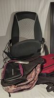 HoMedics massage seat and various bags including red suitcase and patterned bags