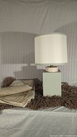 Photo of table lamp on faux fur rug with folded duvet cover beside it