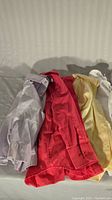 Folded boys dress clothes from left to right showing purple, red, yellow, and white button-up shirts and red pants below