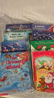 Photo of a stack of Christmas books including Always in a Manger, Laura's Christmas Star, Wake Up Santa Claus!, Ten Christmas Wishes, The 12 Days of Christmas, The Jolliest Christmas Elf, and Santa's New Reindeer.
