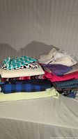Stack of assorted folded fabrics in mixed patterns and colors including chevron and checkered prints