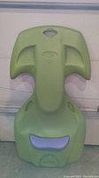 Top view of green molded plastic kayak-shaped water toy with contoured seat and integrated handles.