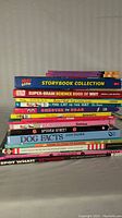 Stack of children's books including a Peppa Pig Storybook Collection, science book, Dr. Seuss's The Cat in the Hat, Dog Facts, and others