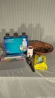 Photo shows all items in the lot on a table including SodaStream bottles in box, VTech kids watch, smart bulb, basket, sticky tabs, cup and a yellow pack of citric acid.
