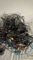 Photo of a tangled pile of electronic wires and cables, showing various types of connectors including RCA and USB.