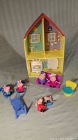 Peppa Pig playhouse with red roof, yellow walls, interior printed details, and figurines with small furniture pieces