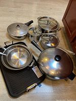 All items grouped on floor: pots, pans, multipan, griddle
