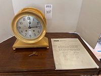 Front view showing clock, winding key, and original sales sheet