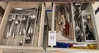 Drawer with assorted J.A. Henckels Zwilling cutlery including forks, spoons, knives, mini goldtone spoons, and knives with wooden handles along with corn holders in white wire trays.