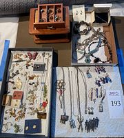 Top view of entire jewelry collection, showing wooden box, rings, earrings, pendants, necklaces, and brooches organized in trays and compartments