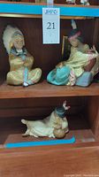 Three porcelain figurines displayed together on shelf