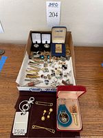 Wide shot showing the complete lot including cuff links, tiepins, keychains, lighter and money holder.