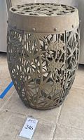 Full front view of the oval metal plant stand with bamboo and flower decor and rivets on side