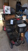 Red and black Go Go Elite Traveller Plus mobility scooter with front basket and rear basket