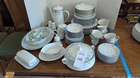 Full view of complete Noritake Blue Hill china set displayed on table, showing all plates, cups, serving pieces, and accessories.