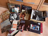 Photo showing assorted vinyl record albums spread on floor, various artists and genres visible