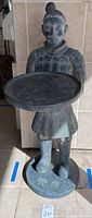 Front view of full statue holding tray on round base