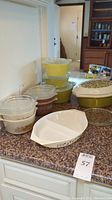 Lots of covered Pyrex oval and round dishes of various patterns and sizes shown on countertop.