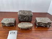 Group of four metal trinket and jewelry boxes displayed on table