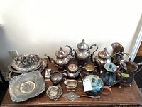 Overview of lot on table showing trays, napkin rings, teapots, small serving pieces