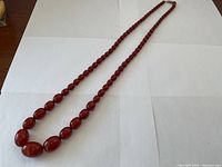 Full length of the 30-inch cherry amber Bakelite bead strand on white background