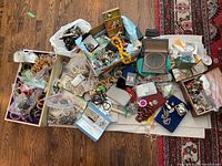 Overview of entire assortment of costume jewelry laid out on floor with boxes and zip-top bags.