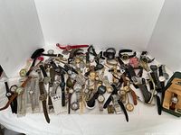 Overview of entire watch lot on white cloth, showing over 30 assorted wristwatches of various styles