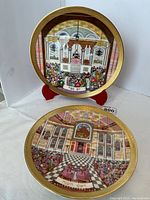 Two Royal Doulton Judaica plates, Yom Kippur and Rosh Hashanah, displayed upright and lying flat showing detailed synagogue interior scenes with congregants and ritual objects, bordered in gold.